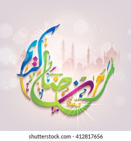 Glossy colourful Arabic Islamic Calligraphy of text Ramadan Kareem in crescent moon shape on mosque silhouetted background.