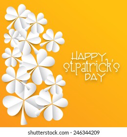 Glossy folded paper shamrock leaves on yellow background for Happy St. Patrick's Day celebration.