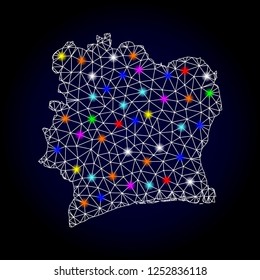Glossy polygonal mesh map of Ivory Coast with glow effect. Vector carcass map of Ivory Coast with glowing multi colored dots for New Year purposes. White mesh lines. Dark blue background.