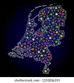 Glossy polygonal mesh map of Netherlands with glare effect. Vector carcass map of Netherlands with glowing multi colored dots for New Year templates. White mesh lines. Dark blue background.