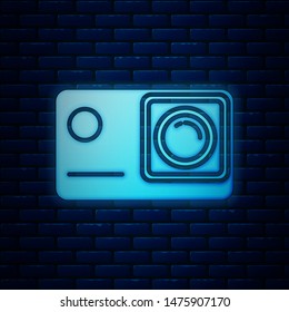 Glowing neon Action extreme camera icon isolated on brick wall background. Video camera equipment for filming extreme sports.  Vector Illustration
