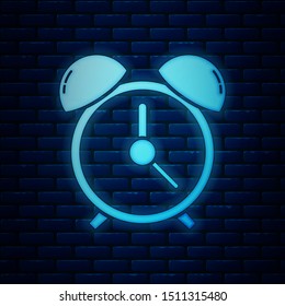 Glowing neon Alarm clock icon isolated on brick wall background. Wake up, get up concept. Time sign.  Vector Illustration
