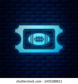 Glowing neon American Football ticket icon isolated on brick wall background.  Vector Illustration