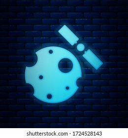 Glowing neon Artificial satellites orbiting the planet Earth in outer space icon isolated on brick wall background. Communication, navigation concept.  Vector Illustration
