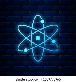 Glowing neon Atom icon isolated on brick wall background. Symbol of science, education, nuclear physics, scientific research. Electrons and protonssign.  Vector Illustration