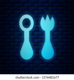 Glowing neon Baby plastic cutlery with fork and spoon icon isolated on brick wall background. Cutlery for kid. Childrens dining items.  Vector Illustration