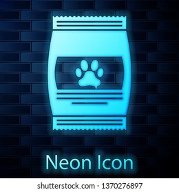 Glowing neon Bag of food for pet icon isolated on brick wall background. Food for animals. Pet food package. Dog or cat paw print. Vector Illustration