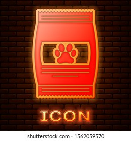 Glowing neon Bag of food for pet icon isolated on brick wall background. Food for animals. Pet food package. Dog or cat paw print.  Vector Illustration