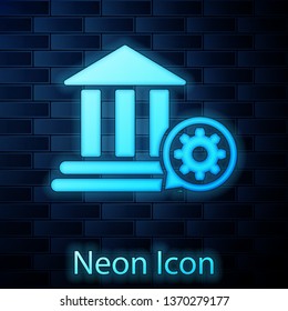 Glowing neon Bank building and gear icon isolated on brick wall background. Adjusting app, service concept, setting options, maintenance, repair, fixing. Vector Illustration