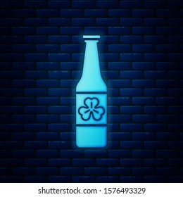 Glowing neon Beer bottle with four leaf clover icon isolated on brick wall background. Happy Saint Patricks day.  Vector Illustration
