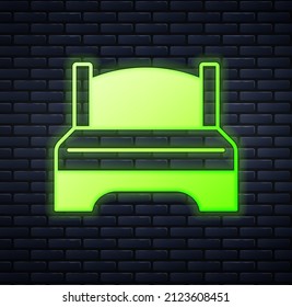 Glowing neon Big bed for two or one person icon isolated on brick wall background.  Vector