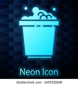 Glowing neon Bucket with soap suds icon isolated on brick wall background. Bowl with water. Washing clothes, cleaning equipment. Vector Illustration