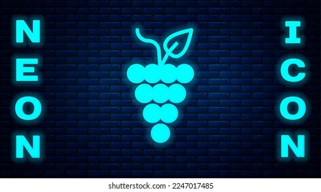 Glowing neon Bunch of grapes icon isolated on brick wall background.  Vector