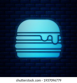 Glowing neon Burger icon isolated on brick wall background. Hamburger icon. Cheeseburger sandwich sign. Fast food menu.  Vector