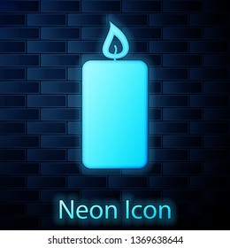 Glowing neon Burning candle icon isolated on brick wall background. Old fashioned lit candle. Cylindrical aromatic candle stick with burning flame. Vector Illustration