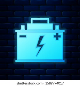 Glowing neon Car battery icon isolated on brick wall background. Accumulator battery energy power and electricity accumulator battery. Lightning bolt symbol.  Vector Illustration