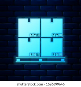 Glowing neon Cardboard boxes on pallet icon isolated on brick wall background. Closed carton delivery packaging box with fragile signs.  Vector Illustration