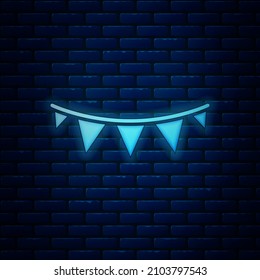 Glowing neon Carnival garland with flags icon isolated on brick wall background. Party pennants for birthday celebration, festival decoration.  Vector