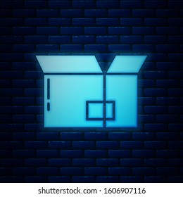 Glowing neon Carton cardboard box icon isolated on brick wall background. Box, package, parcel sign. Delivery and packaging.  Vector Illustration