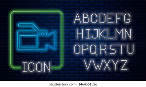 Glowing neon Cinema camera icon isolated on brick wall background. Video camera. Movie sign. Film projector. Neon light alphabet. Vector Illustration