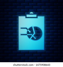 Glowing neon Clipboard with graph chart icon isolated on brick wall background. Report text file icon. Accounting sign. Audit, analysis, planning.  Vector Illustration
