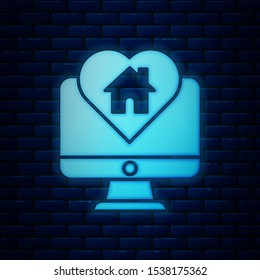 Glowing neon Computer monitor with house in heart shape icon isolated on brick wall background. Love home symbol. Family, real estate and realty.  Vector Illustration