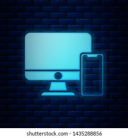 Glowing neon Computer monitor and mobile phone icon isolated on brick wall background. Earnings in the Internet, marketing.  Vector Illustration