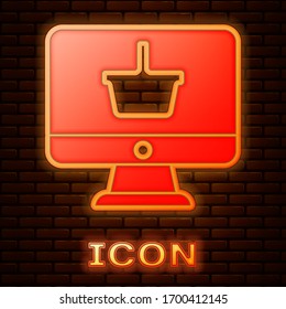 Glowing neon Computer monitor with shopping basket icon isolated on brick wall background. Online Shopping cart. Supermarket basket symbol. Vector Illustration