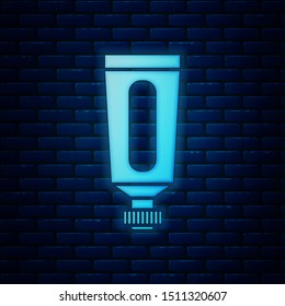 Glowing neon Cream or lotion cosmetic tube icon isolated on brick wall background. Body care products for men.  Vector Illustration