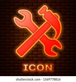 Glowing neon Crossed hammer and wrench icon isolated on brick wall background. Hardware tools.  Vector Illustration