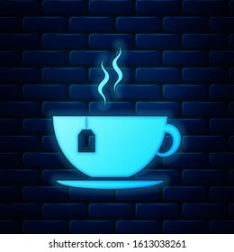 Glowing neon Cup with tea bag icon isolated on brick wall background.  Vector Illustration