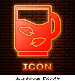 Glowing neon Cup of tea and leaf icon isolated on brick wall background. Vector