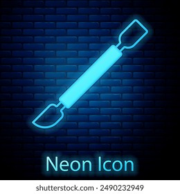 Glowing neon Cuticle pusher icon isolated on brick wall background. Tool for manicure.  Vector