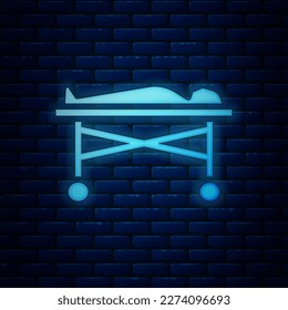 Glowing neon Dead body in the morgue icon isolated on brick wall background.  Vector