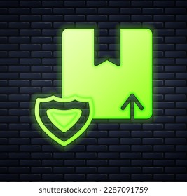 Glowing neon Delivery security with shield icon isolated on brick wall background. Delivery insurance. Insured cardboard boxes beyond the shield.  Vector