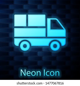 Glowing neon Delivery truck with cardboard boxes behind icon isolated on brick wall background.  Vector Illustration