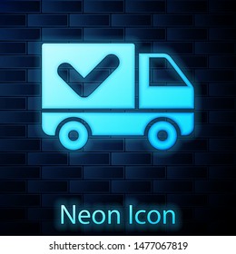 Glowing neon Delivery truck with check mark icon isolated on brick wall background.  Vector Illustration