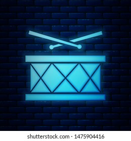 Glowing neon Drum with drum sticks icon isolated on brick wall background. Music sign. Musical instrument symbol.  Vector Illustration