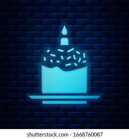 Glowing neon Easter cake and candle icon isolated on brick wall background. Happy Easter.  Vector Illustration
