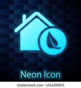 Glowing neon Eco friendly house icon isolated on brick wall background. Eco house with leaf. Vector Illustration