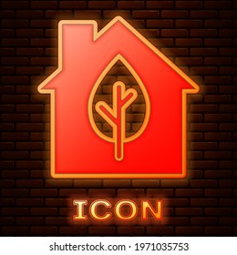 Glowing neon Eco friendly house icon isolated on brick wall background. Eco house with leaf.  Vector