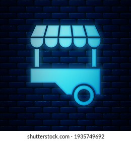 Glowing neon Fast street food cart with awning icon isolated on brick wall background. Urban kiosk.  Vector