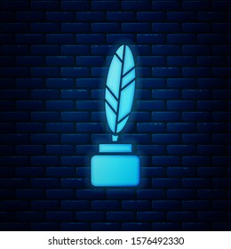 Glowing neon Feather and inkwell icon isolated on brick wall background.  Vector Illustration