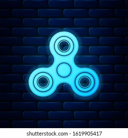 Glowing neon Fidget spinner icon isolated on brick wall background. Stress relieving toy. Trendy hand spinner.  Vector Illustration
