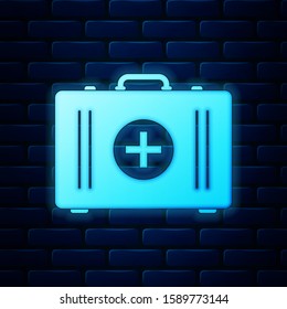 Glowing neon First aid kit icon isolated on brick wall background. Medical box with cross. Medical equipment for emergency. Healthcare concept.  Vector Illustration