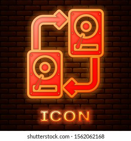 Glowing neon A fixed data storage device hard disk with arrows, data copy icon isolated on brick wall background. Data exchange with hard disk drive.  Vector Illustration