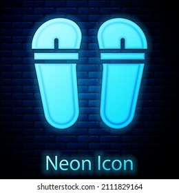 Glowing neon Flip flops icon isolated on brick wall background. Beach slippers sign.  Vector