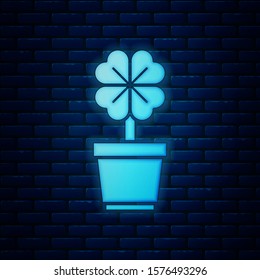 Glowing neon Four leaf clover in pot icon isolated on brick wall background. Happy Saint Patrick day.  Vector Illustration