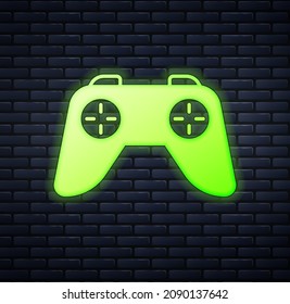 Glowing neon Game controller or joystick for game console icon isolated on brick wall background.  Vector
