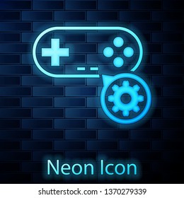 Glowing neon Gamepad and gear icon isolated on brick wall background. Adjusting app, service concept, setting options, maintenance, repair, fixing. Vector Illustration